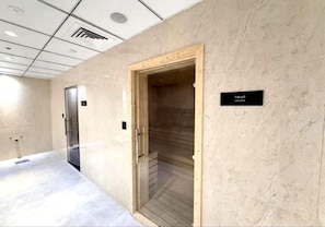 Un passadís amb un espai de sauna, una porta i un senyal que indica la ubicació de la sauna.