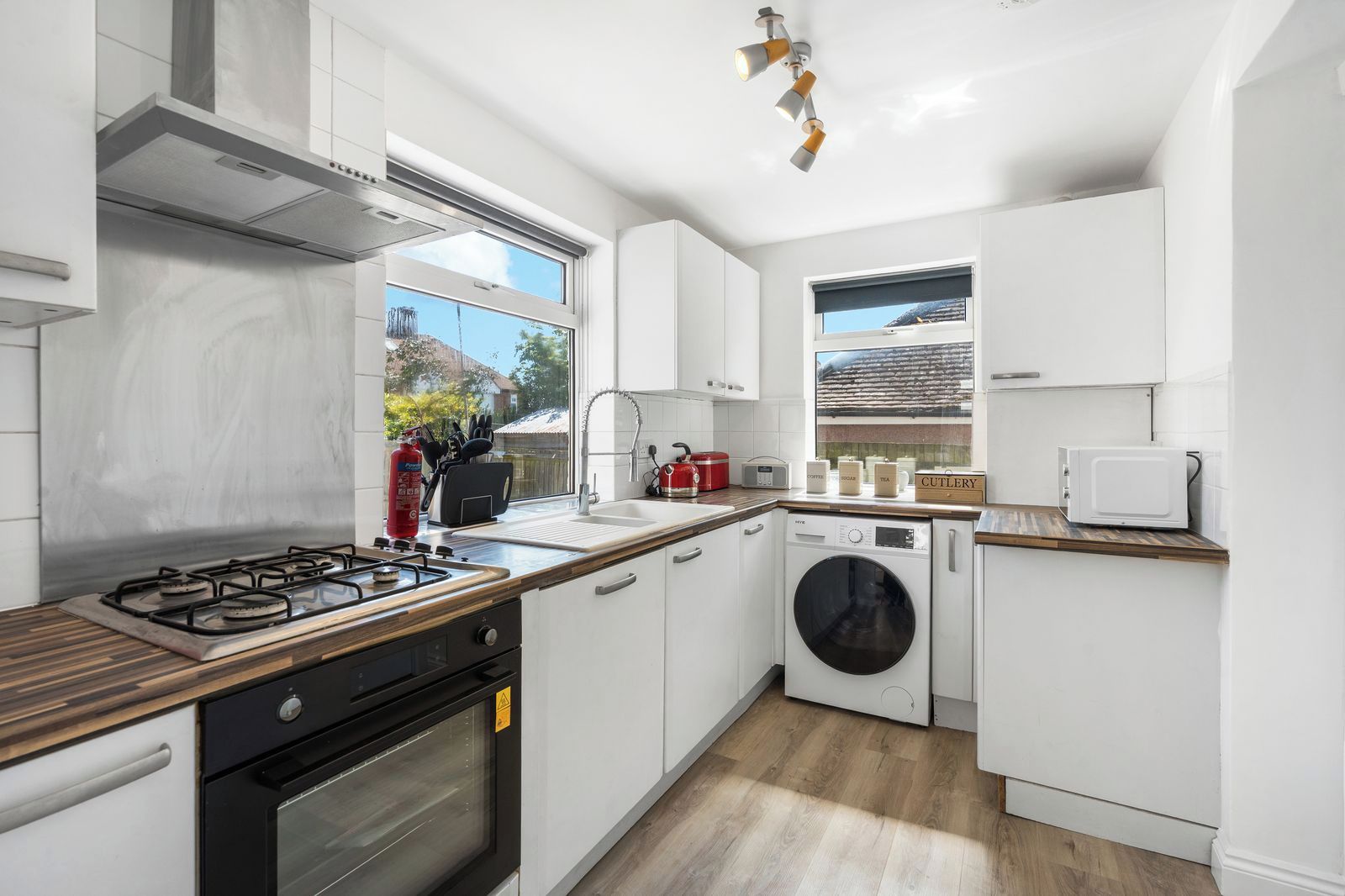 Una cocina moderna con estufa a gas, horno, lavadora integrada y ventana con vista a un edificio.
