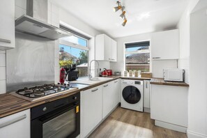 Eine moderne Küche mit Gasherd, Backofen, integriertem Waschmaschine und einem Fenster mit Blick auf ein Gebäude.