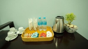 A tray with tea bags, bottled water, a thermos, and a small potted plant on a table.
