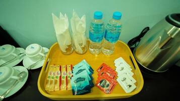 A tray with water bottles, napkins, sugar packets, and coffee packets.