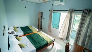 A room with two beds, a ceiling fan, an air conditioning unit, and a window with curtains.