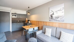 A modern kitchen with grey cabinets, a wooden dining table, and a grey sofa with patterned cushions. - Base With Ski-in/ski-out Access (Auris)