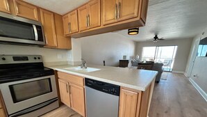 A kitchen with wooden cabinets, a microwave, stove, and dishwasher. - Luxury Beachfront Condo with Seasonally Heated Beachside Pool (Fort Myers Beach)