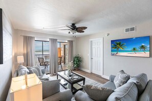 Ein Wohnzimmer mit einer Couch, einem Couchtisch und einem Gemälde mit Strandmotiv.