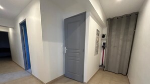 En hall med en grå dörr, en blå dörr och en grå gardin.