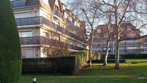 Un edificio residencial con varios balcones, un césped cuidado y un camino pavimentado.