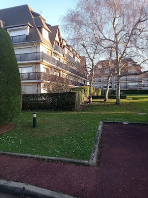 A residential building with multiple balconies, a well-maintained lawn, and a paved pathway. - Cosy apartment 300 metres from the beach (Deauville)