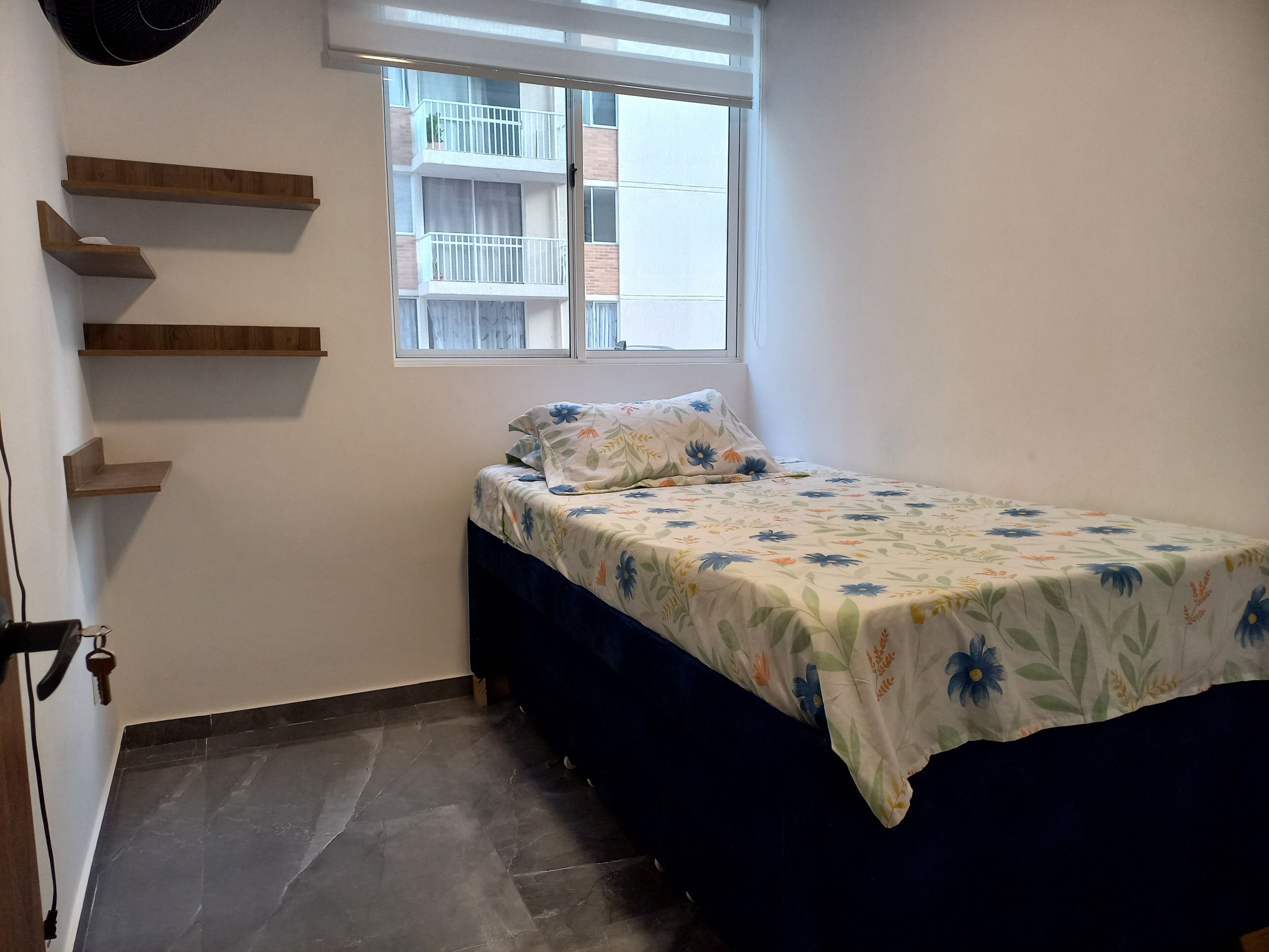 A bedroom with a bed, a window, and built-in shelves.