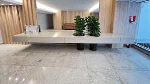 Un área de recepción con un mostrador alargado, un sofá de cuero y plantas en macetas.