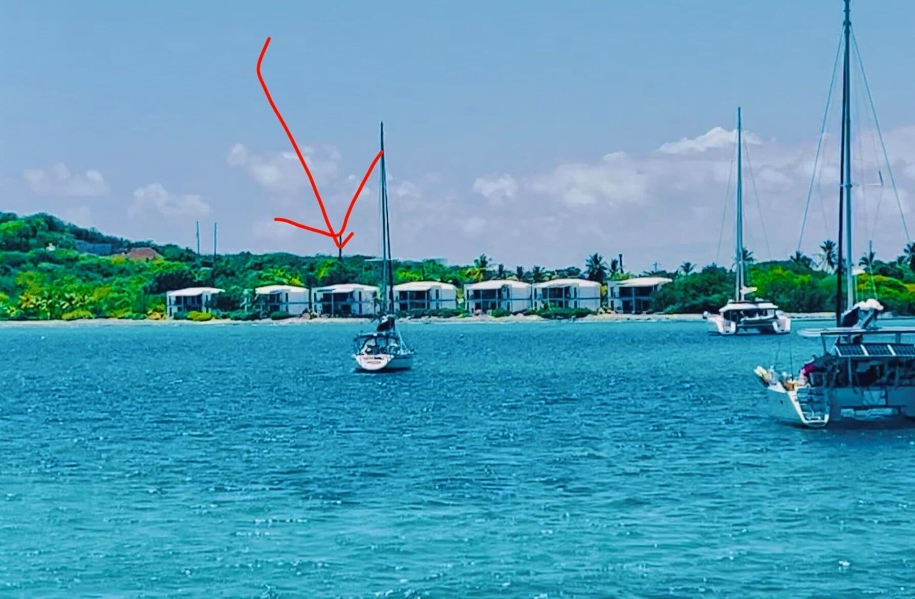 Une zone côtière avec des bateaux, une petite île avec des bâtiments et un ciel dégagé.