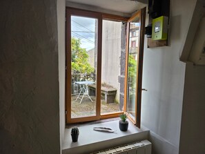 Habitació amb una gran porta corredissa de vidre que dona a un balcó, una petita planta en testos a la finestra i un radiador a sota.