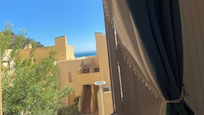 A view through a window with a curtain, revealing a building with a staircase and a clear blue sky. - direct seaside rental (Cerbère)