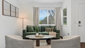 A living room with a green sofa, two armchairs, a coffee table, a floor lamp, and a window with blinds. - 10 MIN to Disney - Family Dream Home-King Bed! (Fullerton)