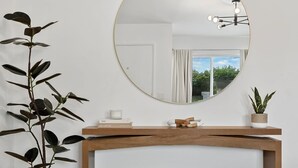A room with a round mirror, a wooden console table, and a potted plant. - 10 MIN to Disney - Family Dream Home-King Bed! (Fullerton)