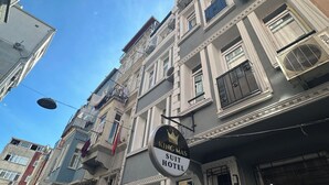 Un edificio de varios pisos con un letrero que indica 'King Mas Suit Hotel', señalando que se trata de un hotel.