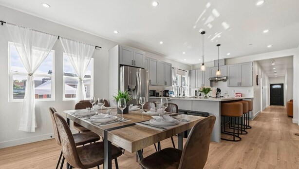 Une cuisine moderne avec un coin repas, un plancher en bois et une vue sur l’extérieur.