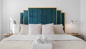 Une chambre d’hôtel avec un grand lit, deux tables de chevet et une tête de lit.