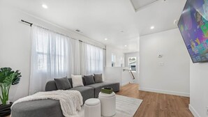 Un salon moderne avec un canapé gris, un plaid blanc et une petite table basse blanche.