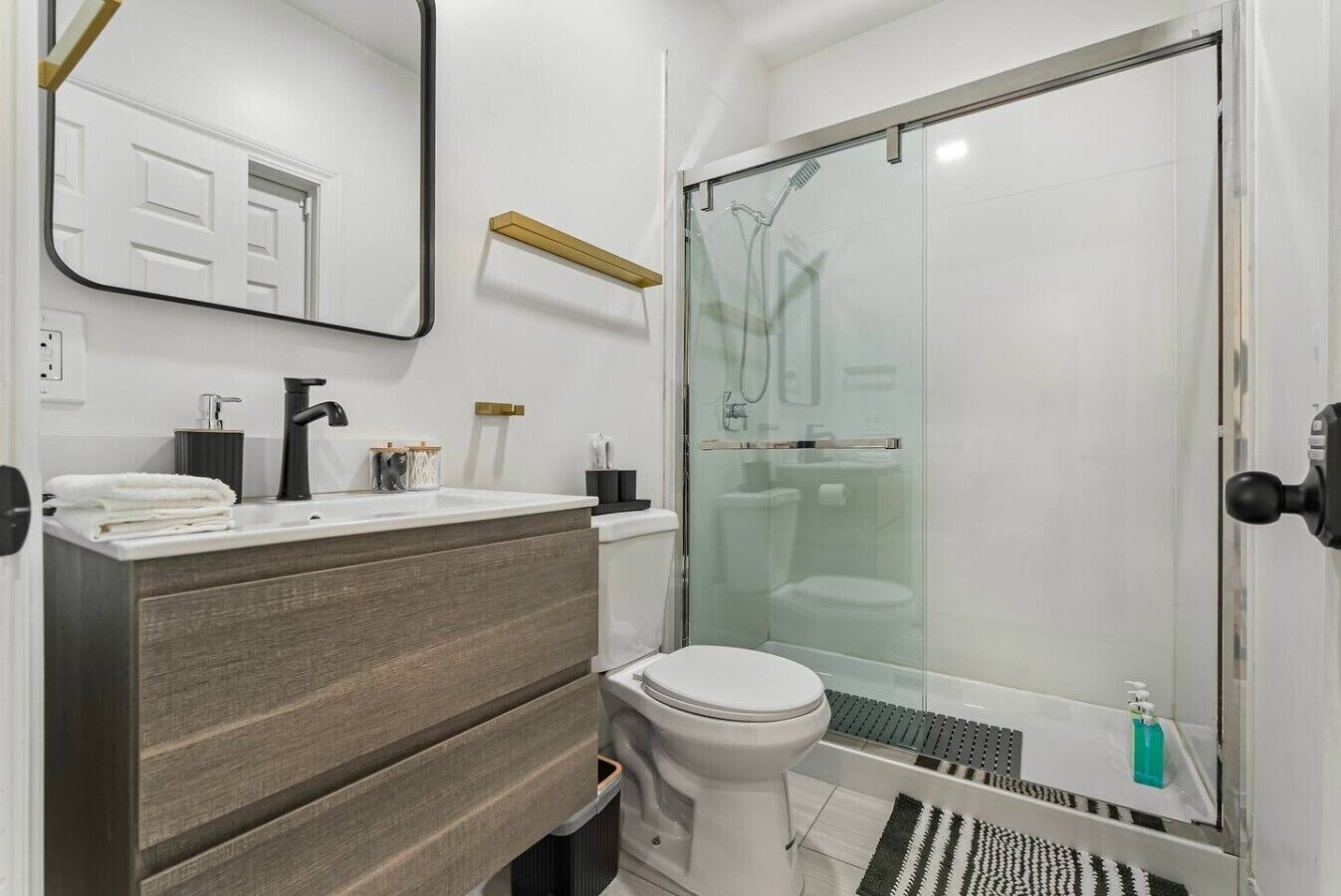 Een moderne badkamer met een douchecabine van glas, een wit toilet en een wastafel met spiegel.