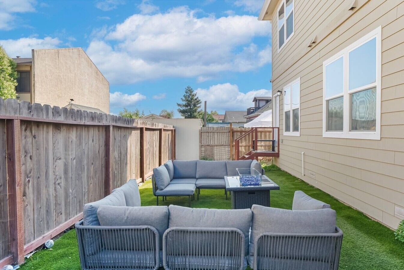Un jardin avec un canapé d’angle, une petite table et une terrasse en bois.