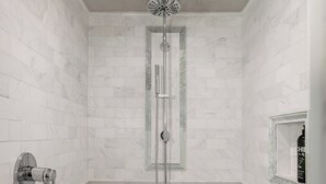 A shower with a glass door, a handheld showerhead, and a bottle of shampoo on a shelf. - Stylish Renovated Telluride 2BR Condo – Walk to Ski, Town, Shops & Restaurants, Sleeps 6 (Telluride)