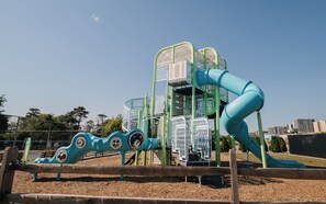 A playground with a slide and climbing structures. - Family Getaway! Modern 2BR Condo + Bonus Bunk Room - Sleeps 8 (Ocean City)