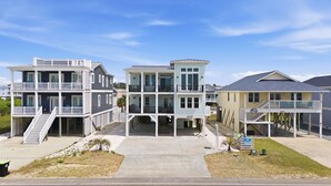 A beachfront property with multiple-story buildings, balconies, and a central walkway. - Ocean Views! One Row to the Beach with Pool & Spa (Oak Island)