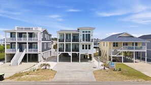 A beachfront property with multiple-story buildings, balconies, and a central walkway. - Ocean Views! One Row to the Beach with Pool & Spa (Oak Island)