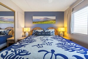 Ein Schlafzimmer mit einem Bett, zwei Nachttischen, einem Wandbild und einem Fenster mit Vorhängen.