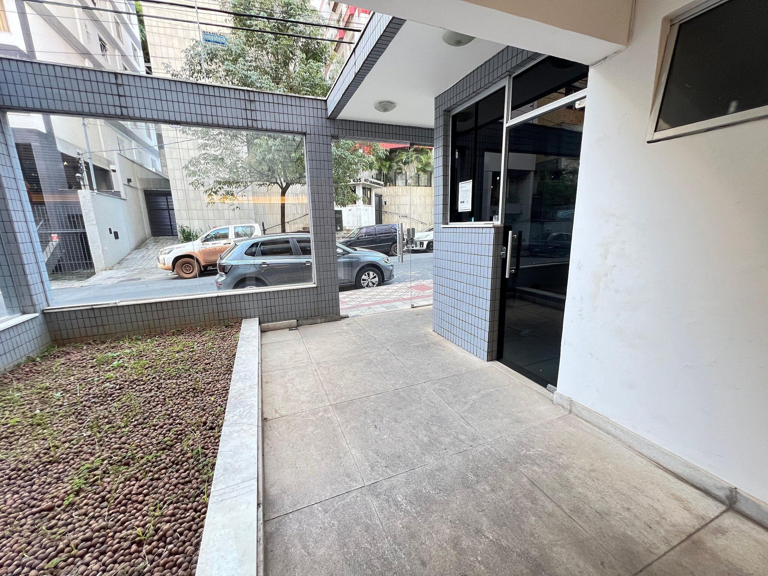 Fachada de edificio con azulejos, puerta de cristal y pequeño espacio exterior con piso de concreto.