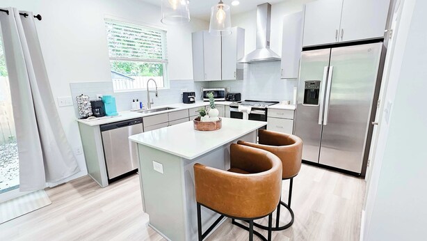Una cucina moderna con isola centrale, elettrodomestici in acciaio inossidabile e illuminazione a sospensione.