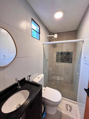 A bathroom with a sink, toilet, and glass-enclosed shower. - Porto Beach Flats (Ipojuca)