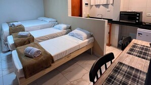 A hotel room with three beds, a kitchenette, and a dining area. - Porto Beach Flats (Ipojuca)