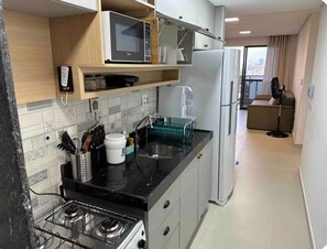A modern kitchen with a gas stove, microwave, and refrigerator. - Park Del Prado 801 · Your home on Intermares beach (Cabedelo)