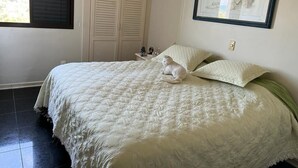 A bedroom with a bed, a window with blinds, a closet, and a framed picture on the wall.