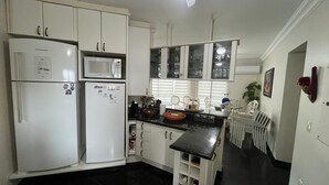 A kitchen with white cabinets, a black countertop, a microwave, and a refrigerator.