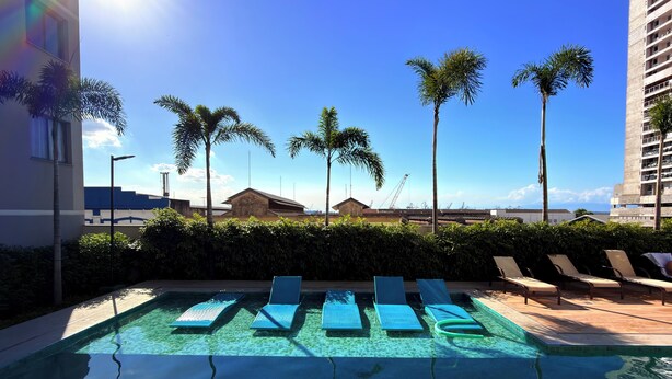 A clear swimming pool with lounge chairs, palm trees, and a view of the ocean and buildings. - Downtown Rio • VLT at the Door • Pool • Wi-Fi • 20 min Copacabana. (Rio de Janeiro)