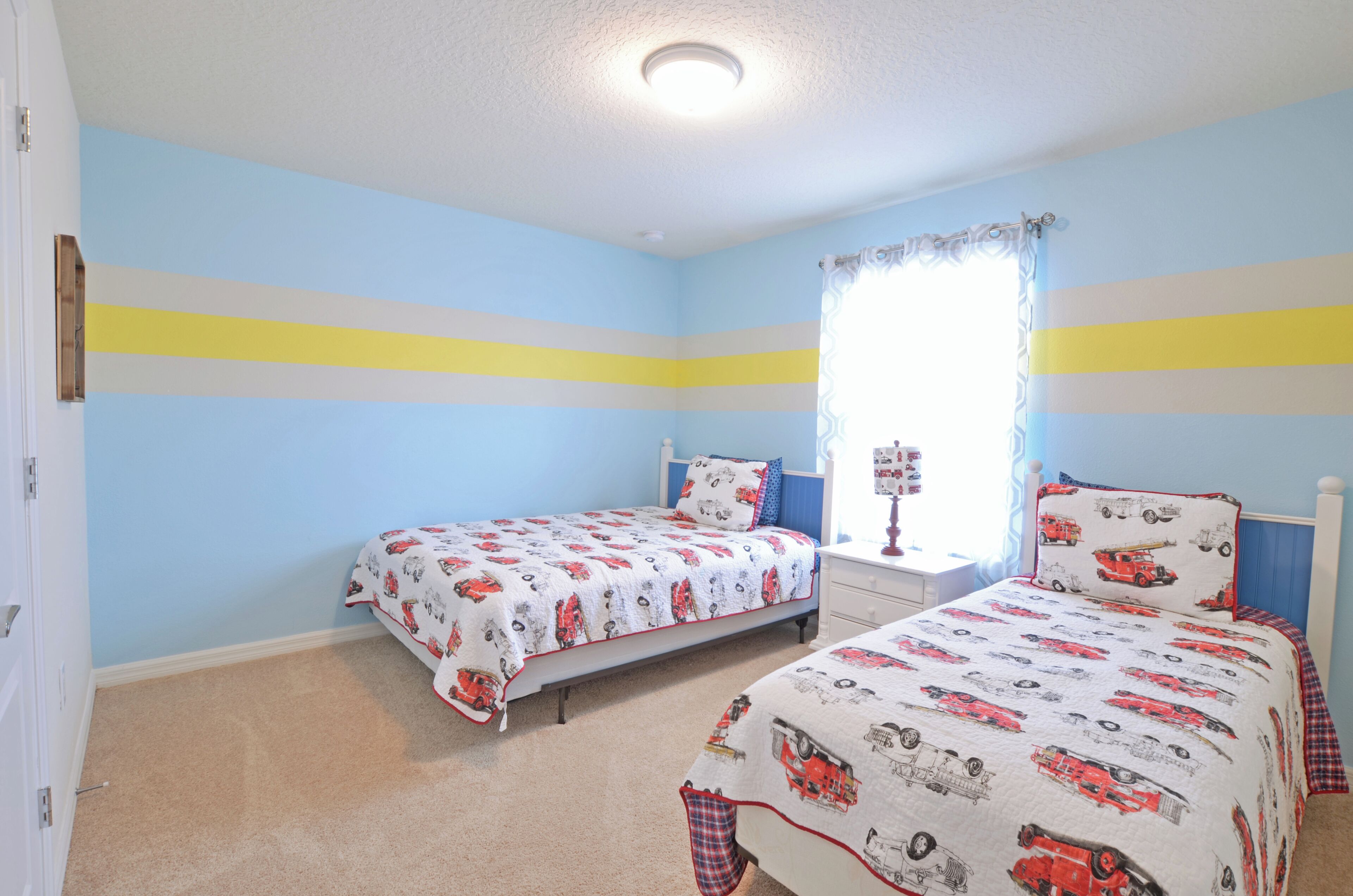 Une chambre avec deux lits, une fenêtre avec des rideaux et une porte.
