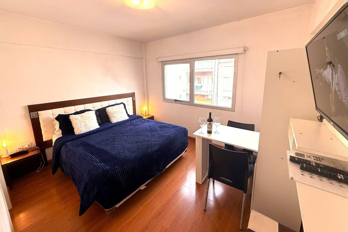 Un dormitorio con una cama, un escritorio, una silla, un televisor y una ventana.