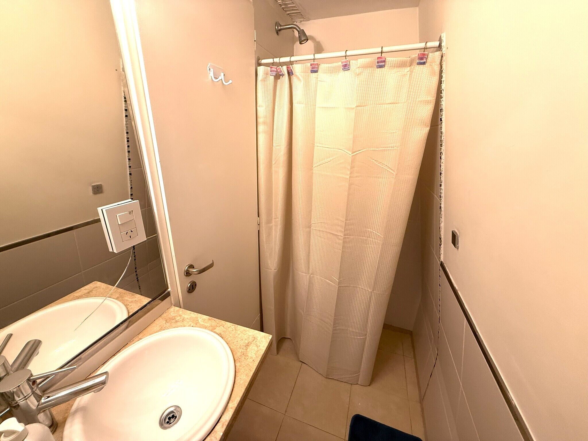 A bathroom with a double sink, a shower curtain, and a towel rack.