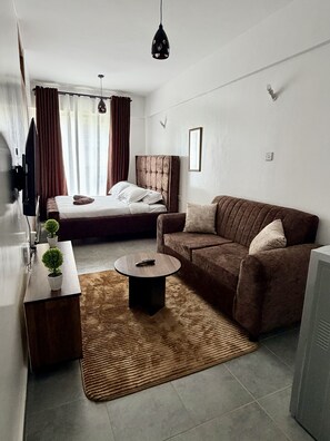 Ein modernes Hotelzimmer mit Bett, Sofa, Couchtisch und Fernseher.