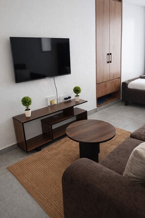 Ein modernes Wohnzimmer mit Flachbildfernseher, Holzschrank, rundem Couchtisch und braunem Sofa.