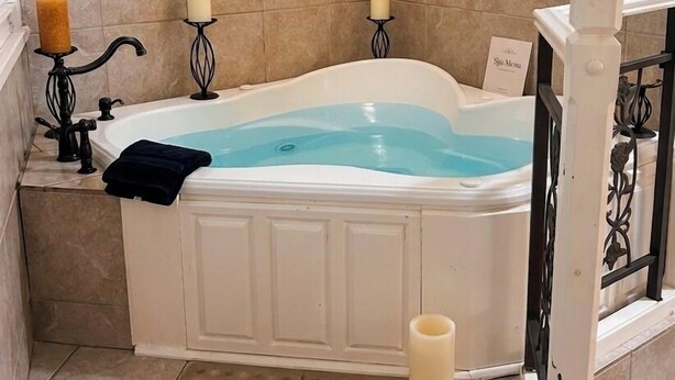 A bathroom with a freestanding bathtub, a wall-mounted music-themed decoration, and three lit candles.