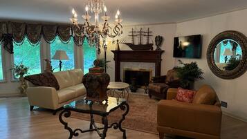 A living room with a chandelier, a fireplace, a sofa, a coffee table, and a large mirror.