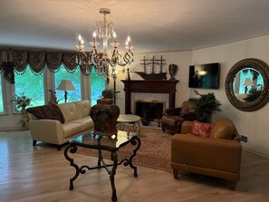 A living room with a chandelier, a fireplace, a sofa, a coffee table, and a large mirror.