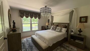 A bedroom with a large bed, a chandelier, a view of the outdoors, and a statue on a dresser.