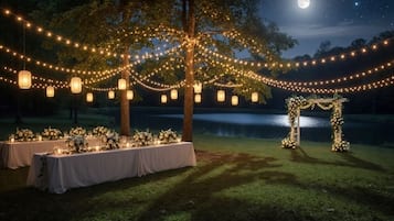 An outdoor wedding setup with string lights, lanterns, and floral arrangements under a night sky.