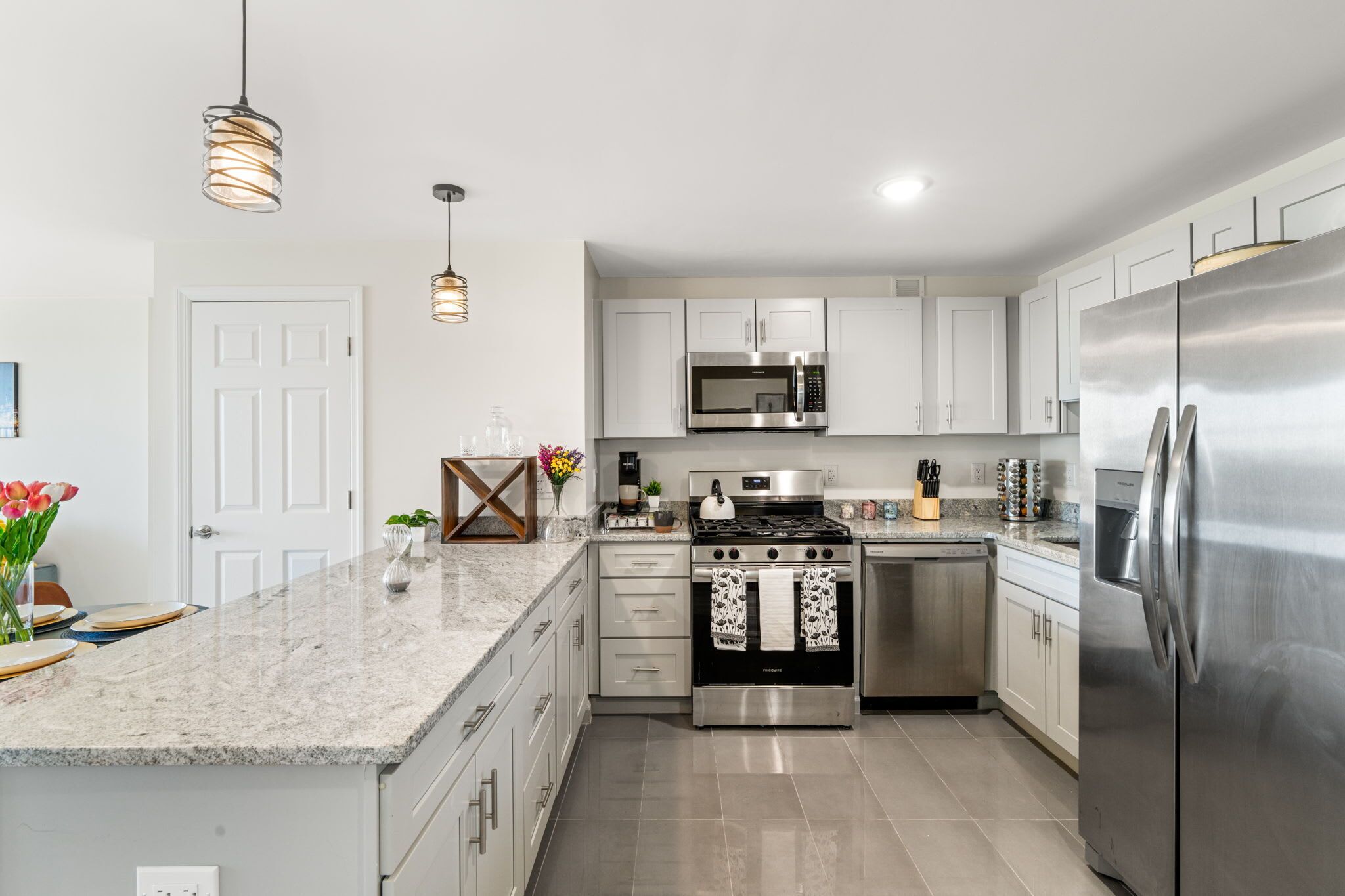 A modern kitchen with stainless steel appliances, a marble countertop, and pendant lighting.