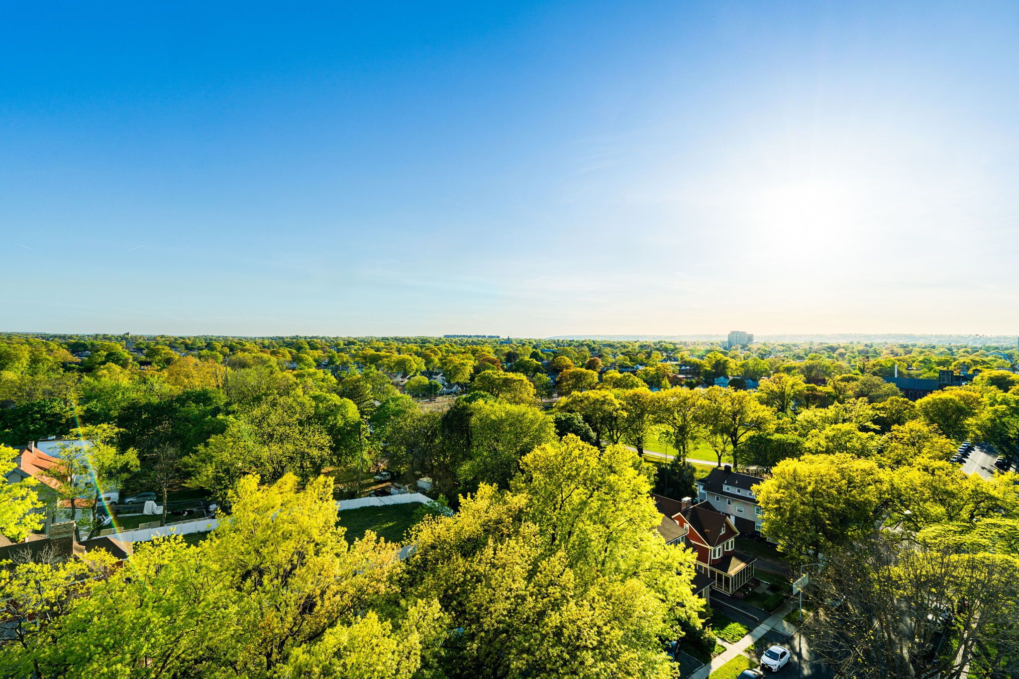 An aerial view of a residential area with houses, trees, and a clear sky.